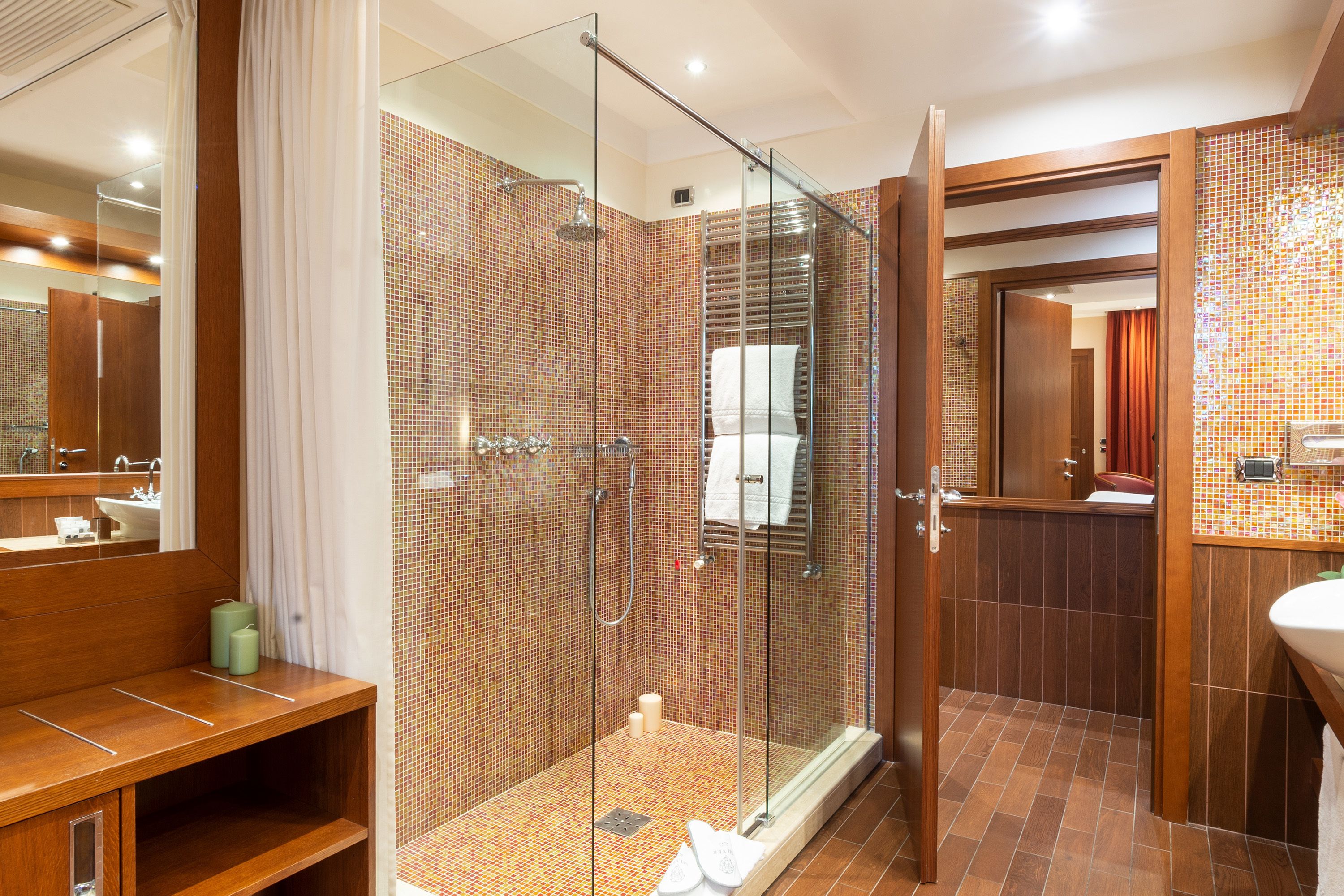 A modern bathroom with a glass-enclosed shower, a wooden vanity, and a tiled shower area.