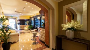 A lobby with a reception desk, seating area, and a large mirror. - Hotel Silver (Milan)