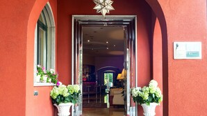 A hotel entrance with a red exterior, a star-shaped light fixture above the door, and a red doormat with the hotel's name. - Hotel Silver (Milan)
