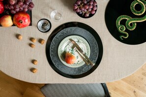 A dining table with a plate, a fork, a knife, and a bowl of grapes.