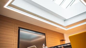 A modern conference room with a large skylight, a flat-screen TV, and a marble floor.
