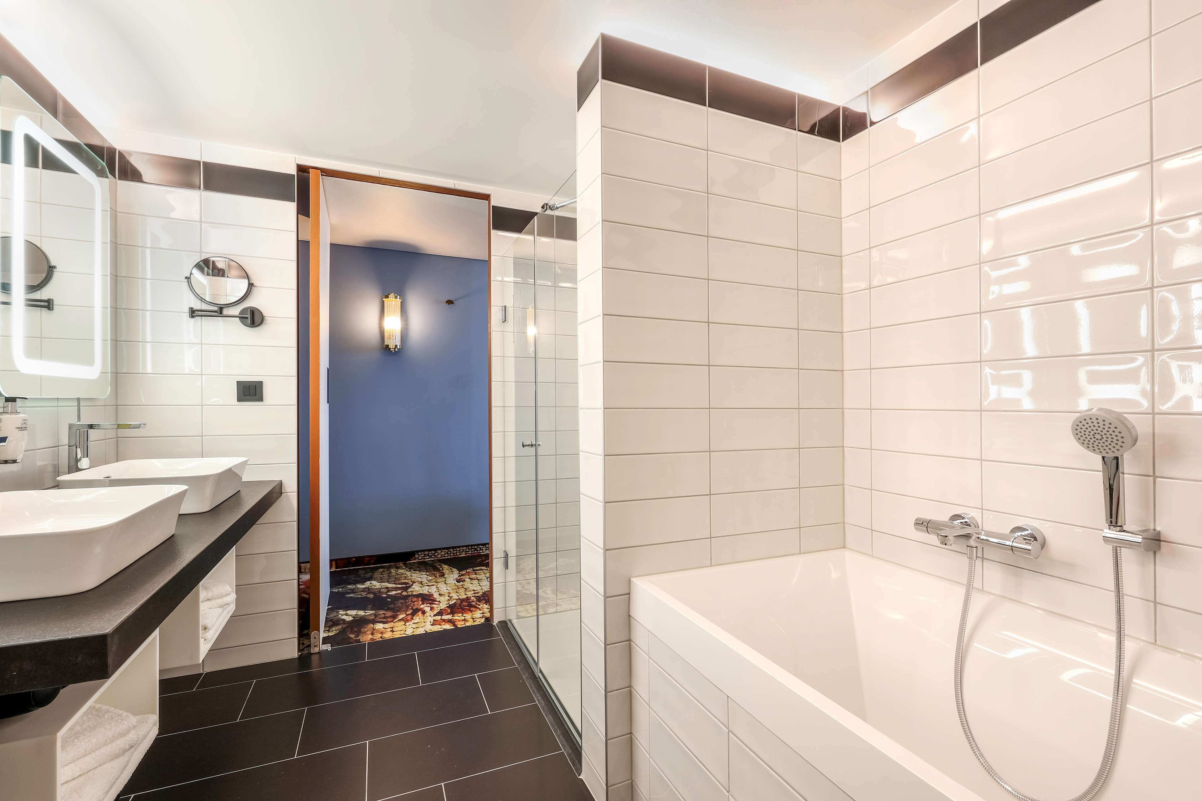 Een moderne badkamer met een groot bad, een douche en twee wastafels.