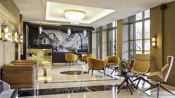 A modern lobby with a central seating area, a large window, and a mural of a train.