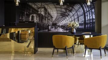 A modern reception area with a curved ceiling, a reception desk, and two yellow chairs.