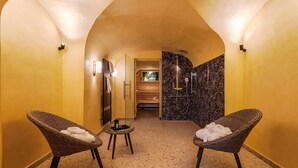 Un espace détente avec deux fauteuils en osier, une petite table et un espace douche doté d’un mur en marbre noir.