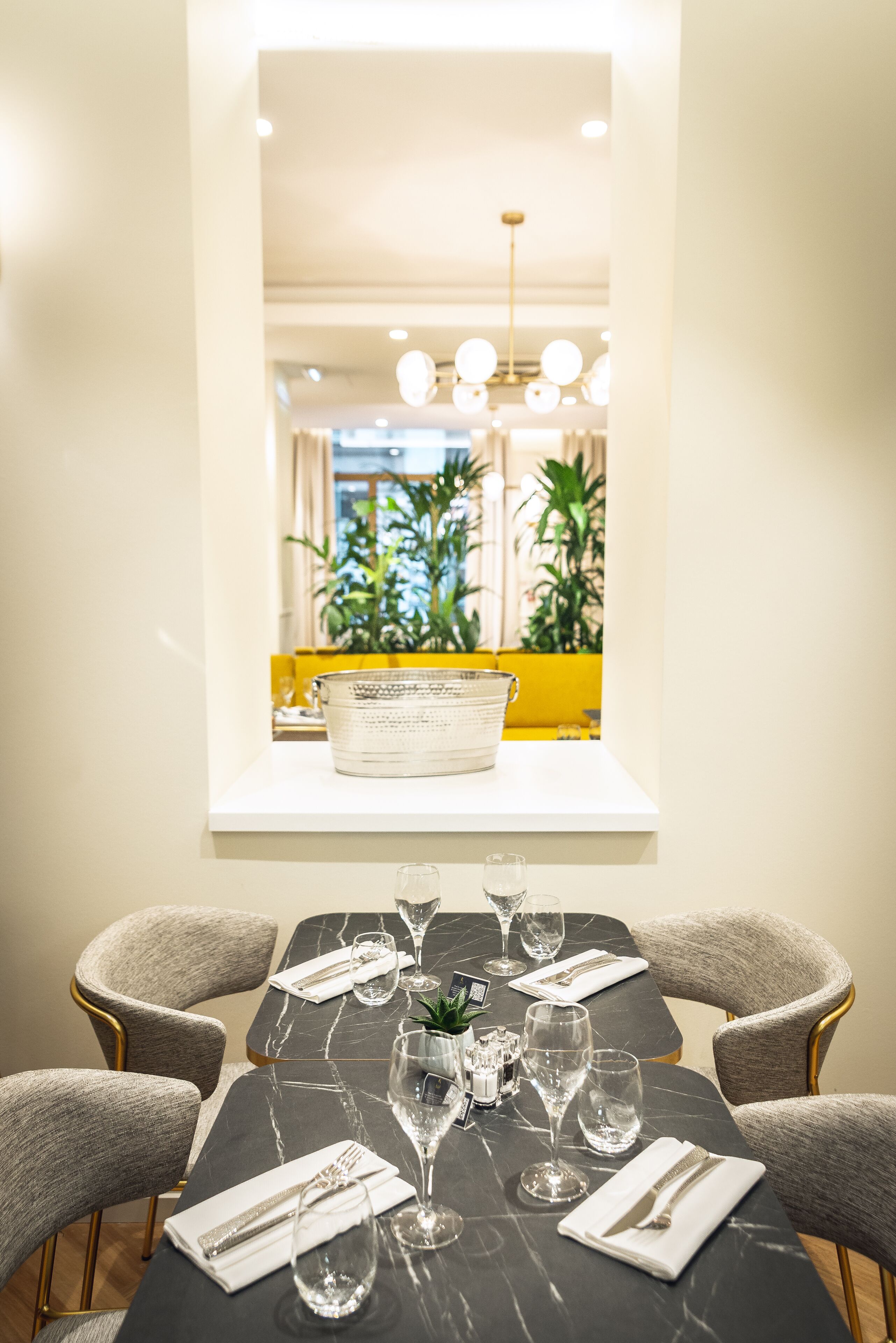 Un comedor con una mesa de mármol, sillas tapizadas en gris y una pared blanca.