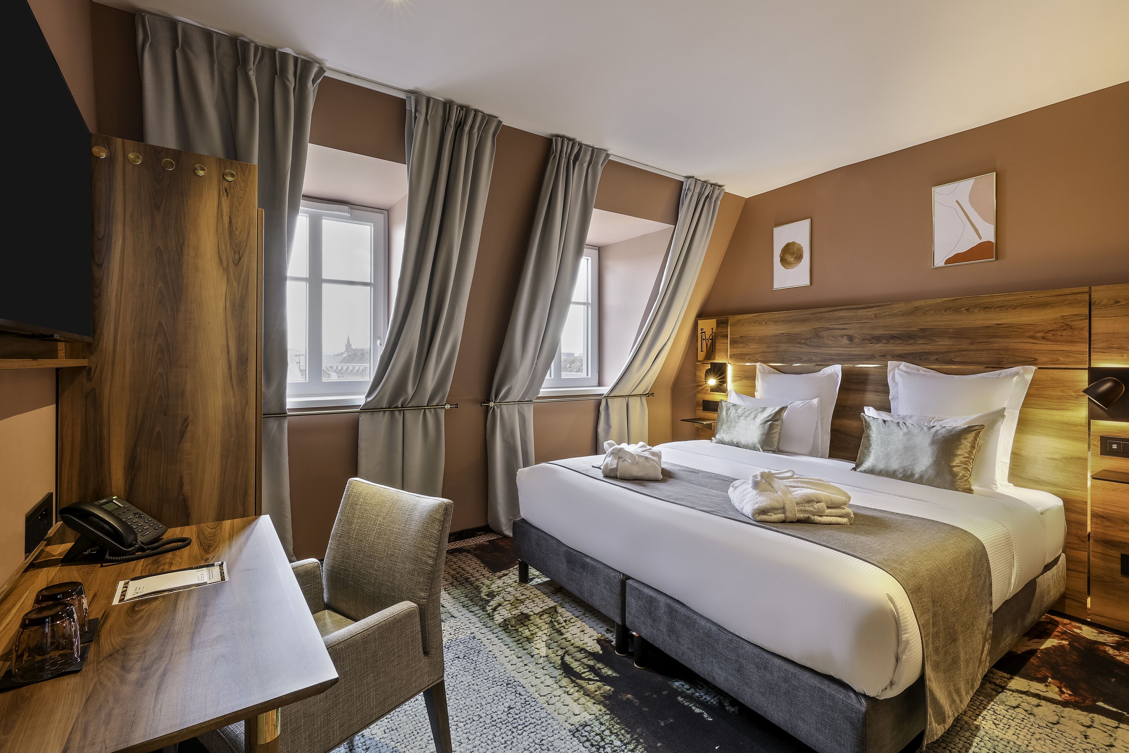 A hotel room with a bed, a desk, a chair, and a telephone.
