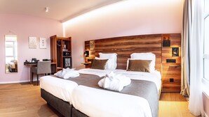 Une chambre d’hôtel moderne équipée d’un grand lit, d’un bureau, d’une armoire et d’un miroir.