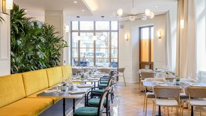 Un restaurant doté d’un coin salon avec des banquettes jaunes, de plusieurs tables avec des chaises et de grandes fenêtres donnant sur la rue.