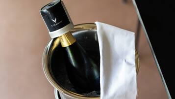 Una bottiglia di vino con etichetta nera e dorata, parzialmente avvolta in un panno bianco, posta in un contenitore metallico.
