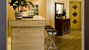 A reception area with a wooden reception desk, a potted plant, a mirror, and a cabinet with decorative items. - Hotel Noce (Brescia)
