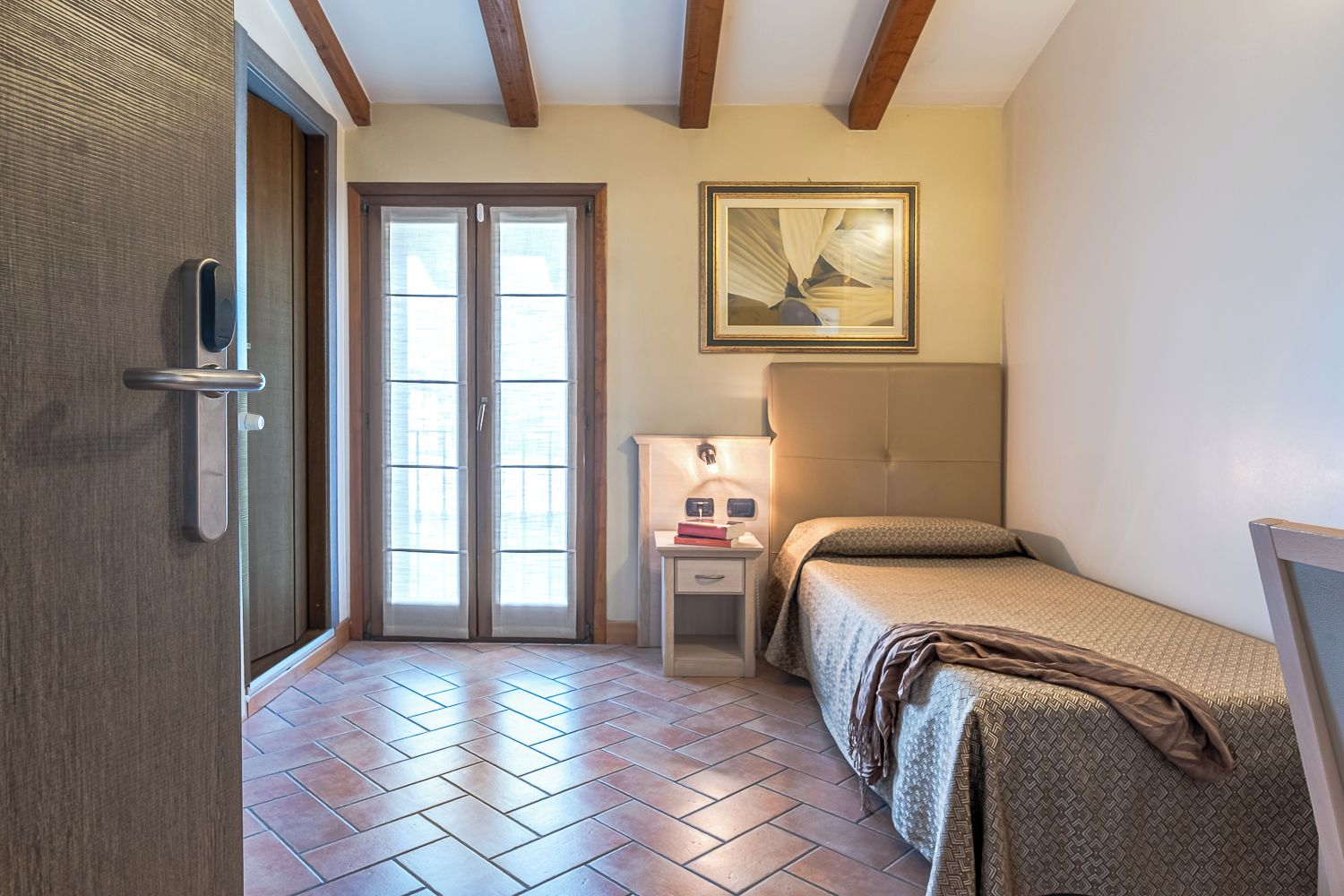 Une chambre à coucher avec un lit, une table de chevet, une lampe et une porte dotée d’une poignée.