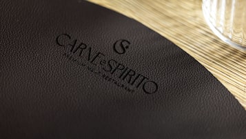 Eine schwarze Lederkarte mit geprägtem Text 'CARNE SPIRITO' und 'PREMIUM RESTAURANT', die ein gehobenes Restaurant kennzeichnet.