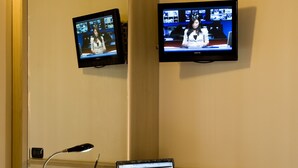 A hotel room with a desk, two monitors, a laptop, a chair, and a desk lamp. - Hotel Noce (Brescia)
