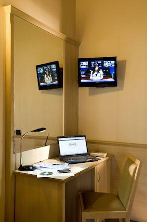 A hotel room with a desk, two monitors, a laptop, a chair, and a desk lamp. - Hotel Noce (Brescia)