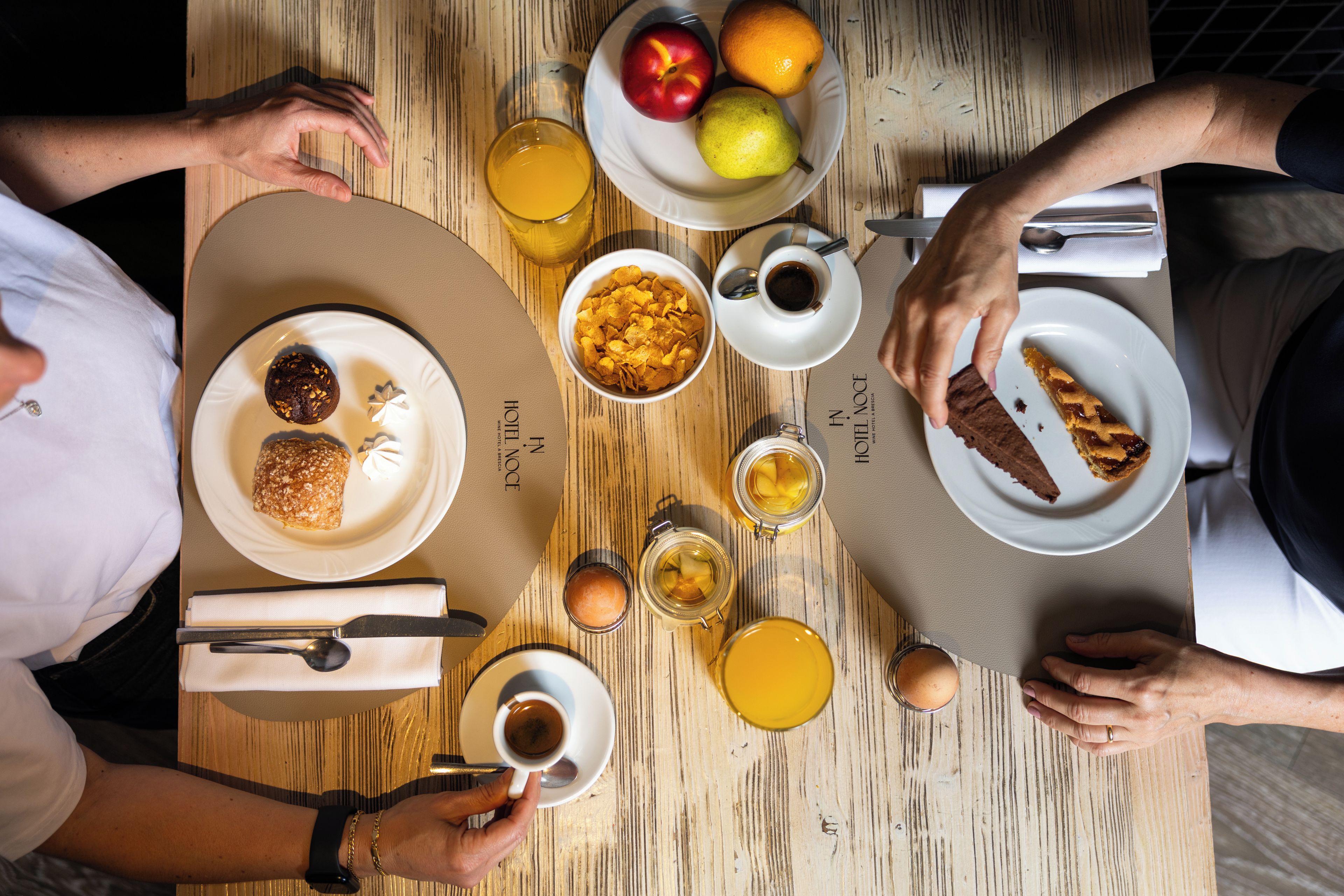 A dining table with plates of food, glasses of orange juice, and a bottle of wine.