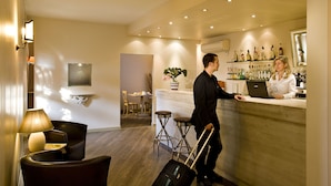 A hotel lobby with a reception desk, bar area, seating, and a potted plant. - Hotel Noce (Brescia)
