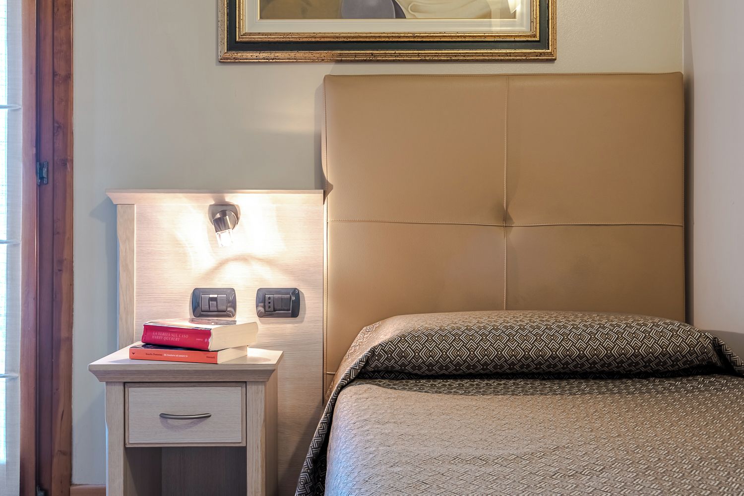 Un dormitorio con cama, una mesita de noche con lámpara y una lámpara de pared.