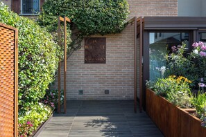Un muro de ladrillo con una pérgola de madera y un letrero.