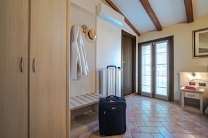 A hotel room with a wooden wardrobe, a radiator, a suitcase, and a bedside table with a lamp. - Hotel Noce (Brescia)