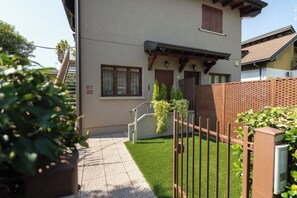 Un edificio residencial con acceso pavimentado, cerca de madera y un pequeño jardín.