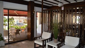Um hall de hotel com móveis de madeira, um ventilador de teto e vista para a rua.