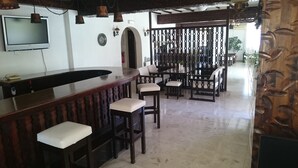 Uma área de bar com bancos de madeira e uma TV fixada na parede.