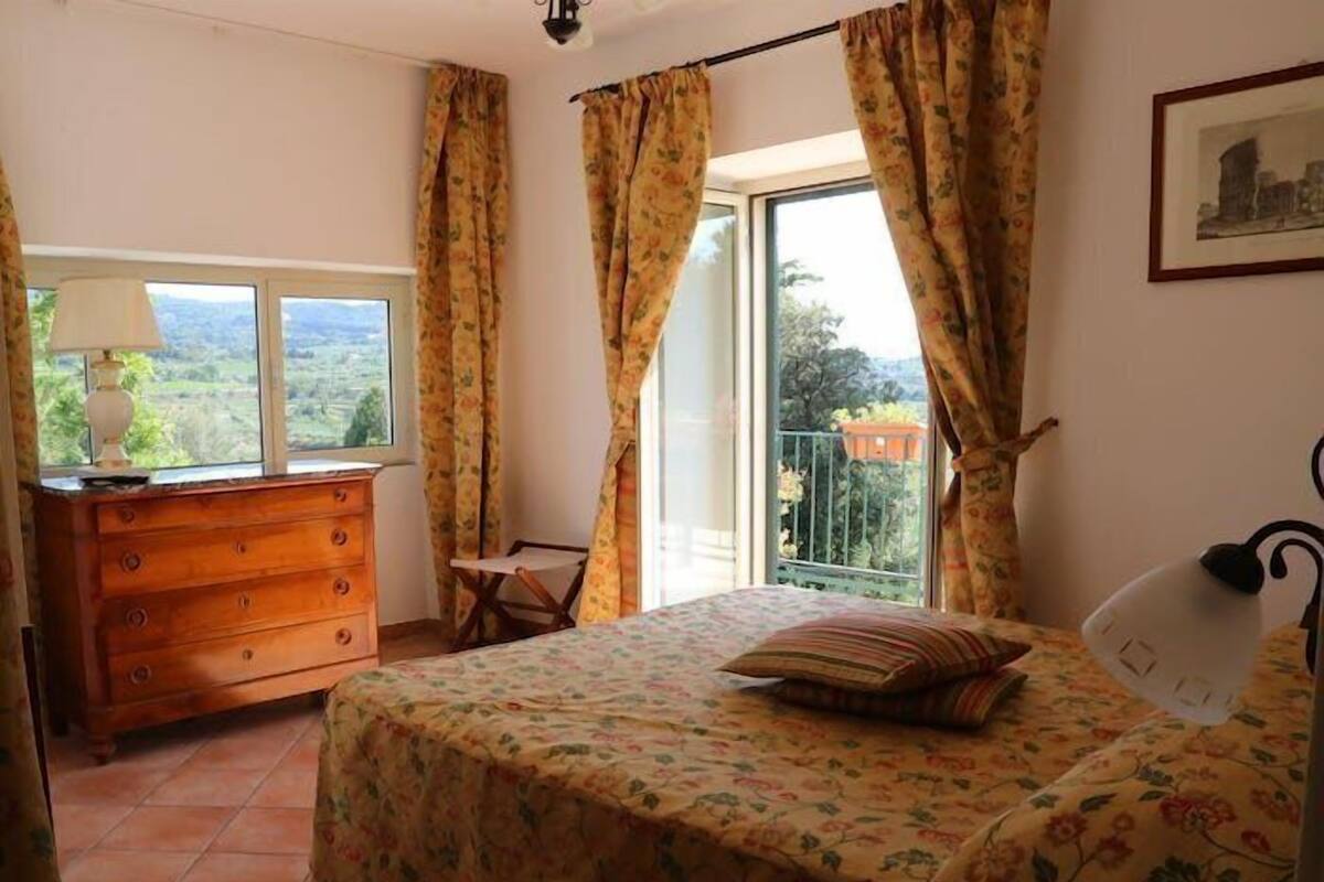 A bedroom with a bed, dresser, and a view of the outdoors.