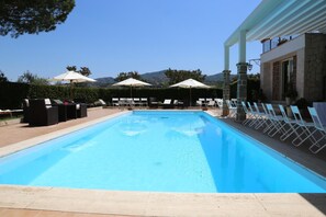 A swimming pool with lounge chairs and umbrellas, surrounded by stone pillars and a building with a balcony. - Tenuta di Pietra Porzia (Frascati)