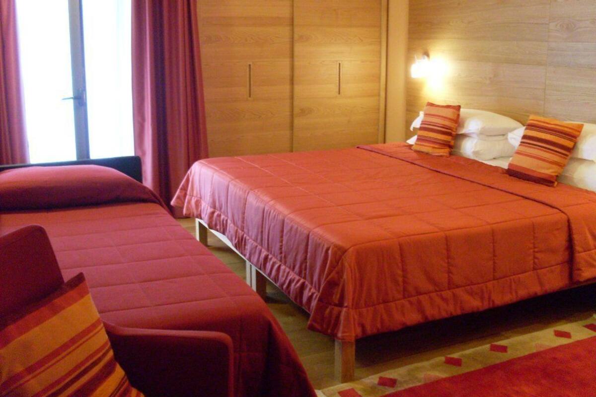 Une chambre d’hôtel avec deux lits, une armoire en bois et une table de chevet avec une lampe.