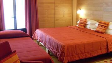 Ein Hotelzimmer mit zwei Betten, einem Holzschrank und einem Nachttisch mit Lampe.