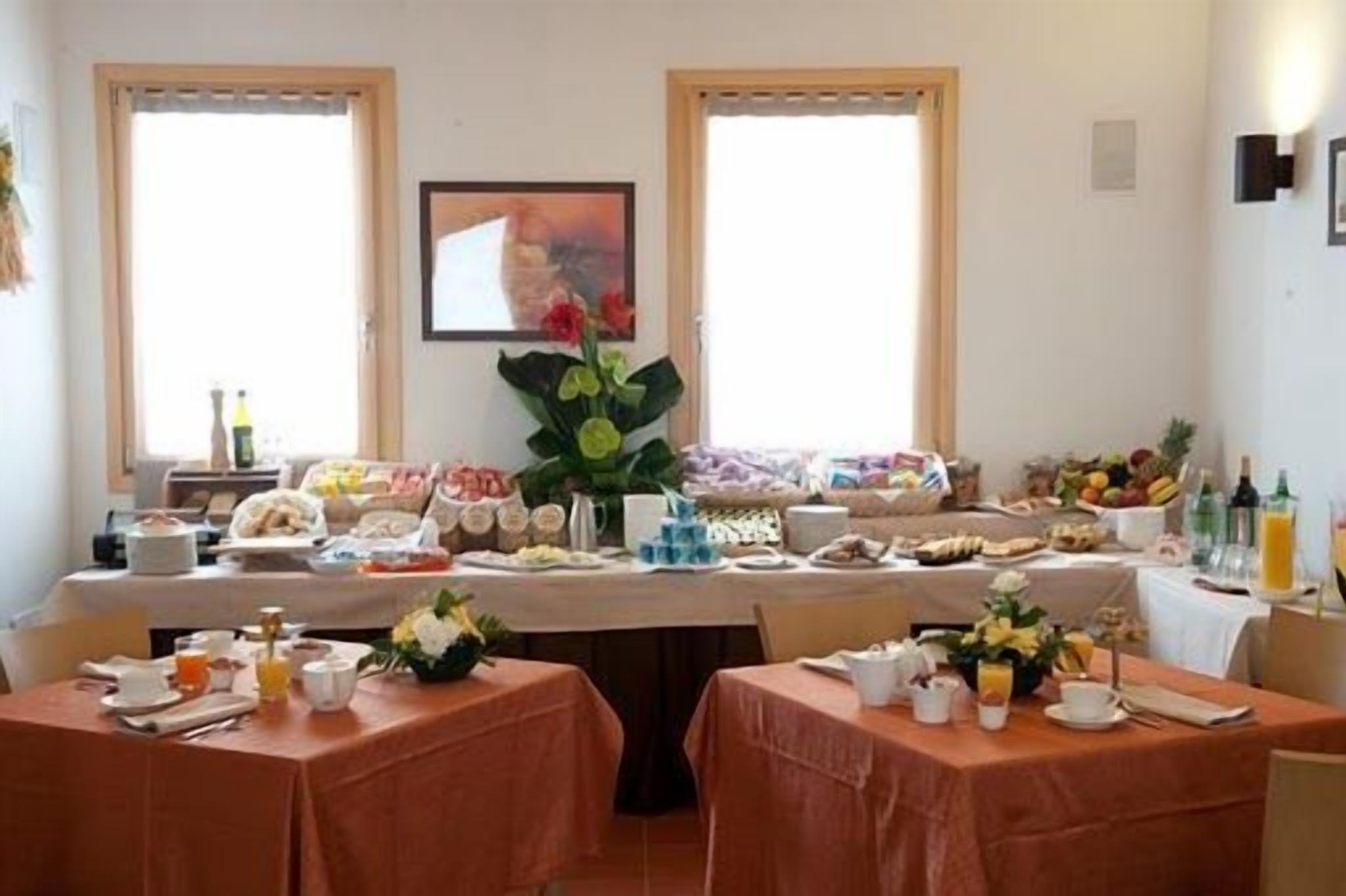 A breakfast buffet with various food items and beverages, arranged on tables with orange tablecloths.