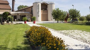 A hotel with a modern design, featuring a prominent entrance with a sign, a well-maintained lawn, and a pathway leading to the entrance.