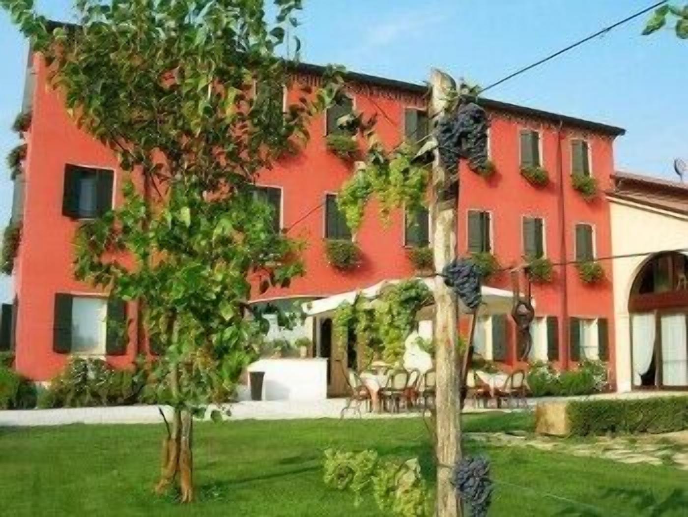 Un edifici vermell amb nombroses finestres i un jardí al davant.