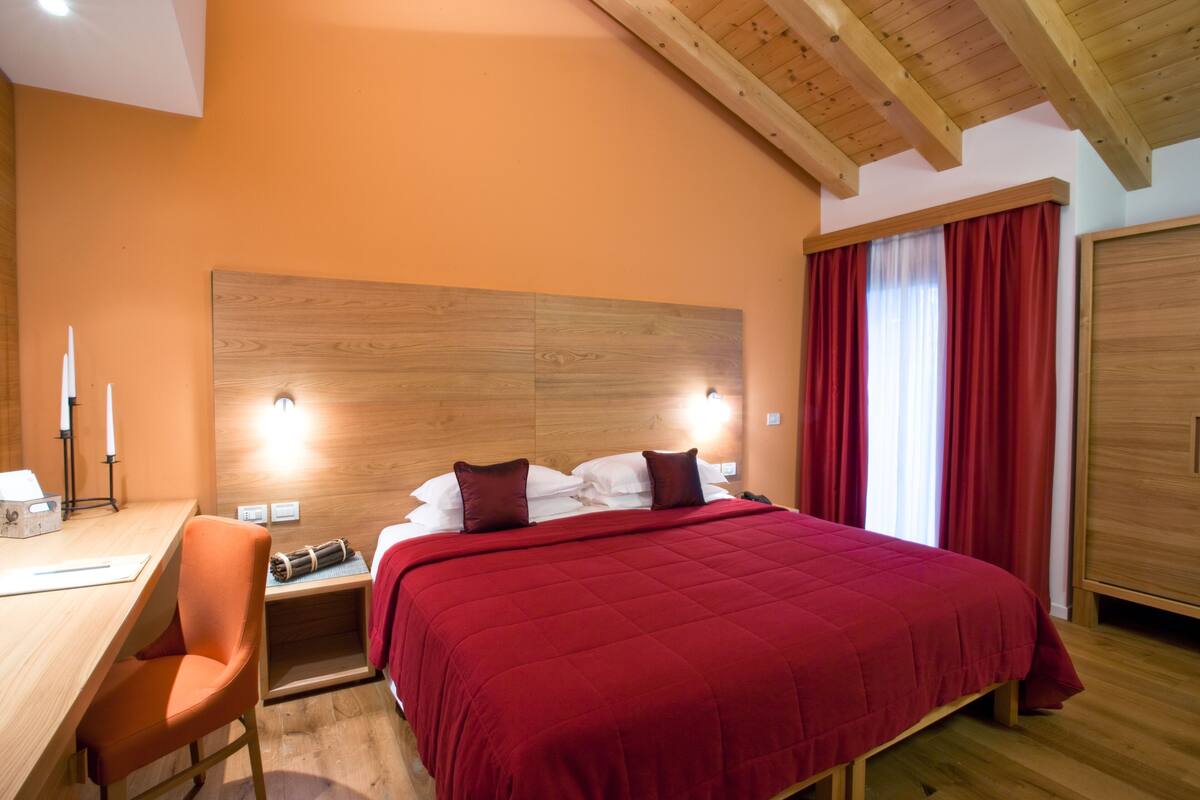 Une chambre à coucher avec un grand lit, une tête de lit en bois et des rideaux rouges.