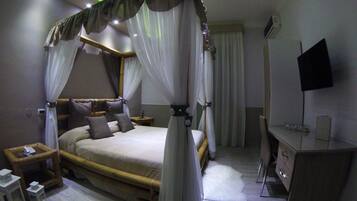 Ein Schlafzimmer mit Himmelbett, Nachttischen, Schreibtisch und Flachbildfernseher.