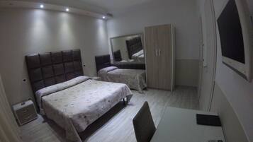 Un dormitorio con cama, armario, escritorio y televisor.