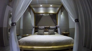 A bed with a wooden frame and white bedding, surrounded by white curtains.