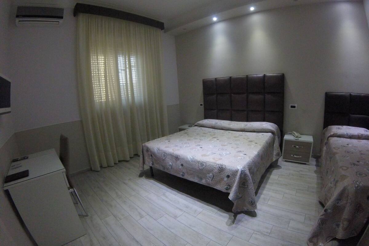 A bedroom with a bed, bedside tables, a wardrobe, and a desk.