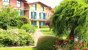 A multi-story building with balconies, surrounded by well-maintained gardens and flowering plants. - Hotel Residence Montelago (Ternate)