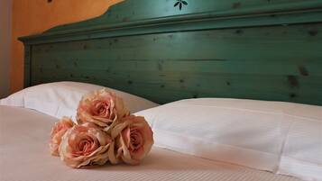 Una cama con sábanas blancas y un ramo de rosas rosadas.