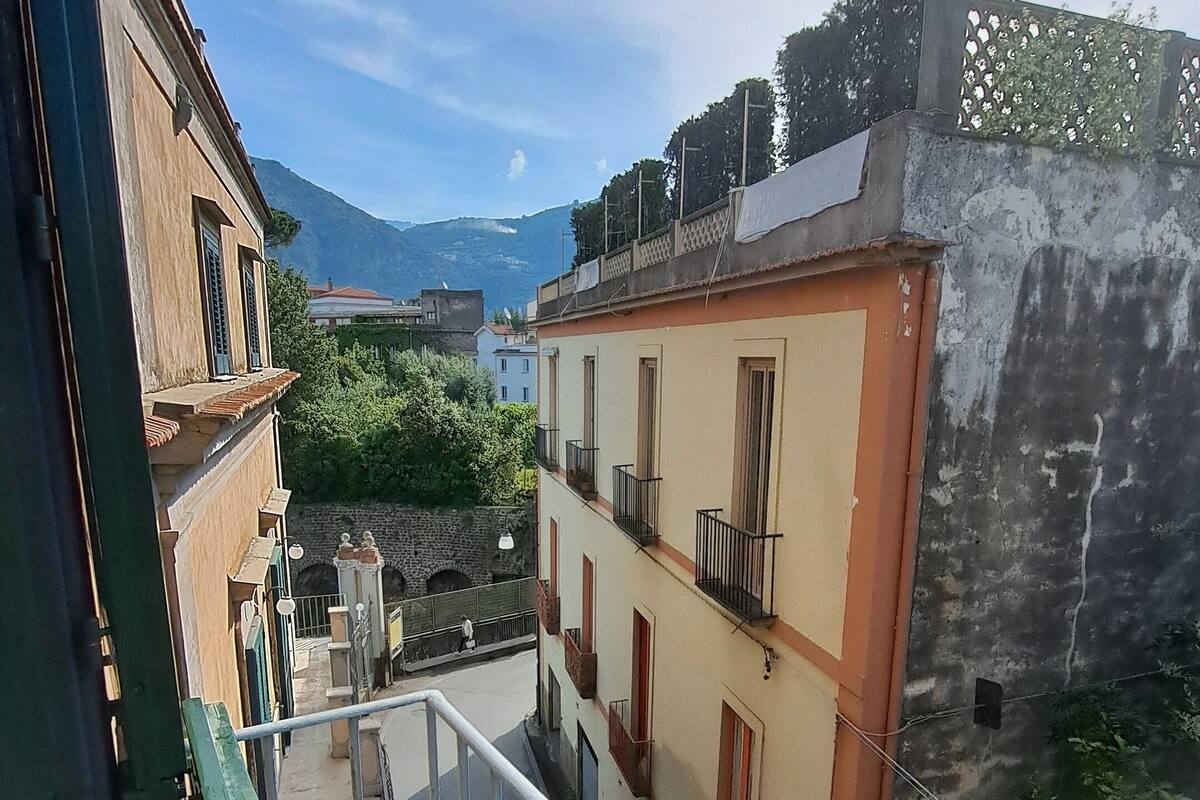 A balcony with a view of a mountain and a building with a stone wall.