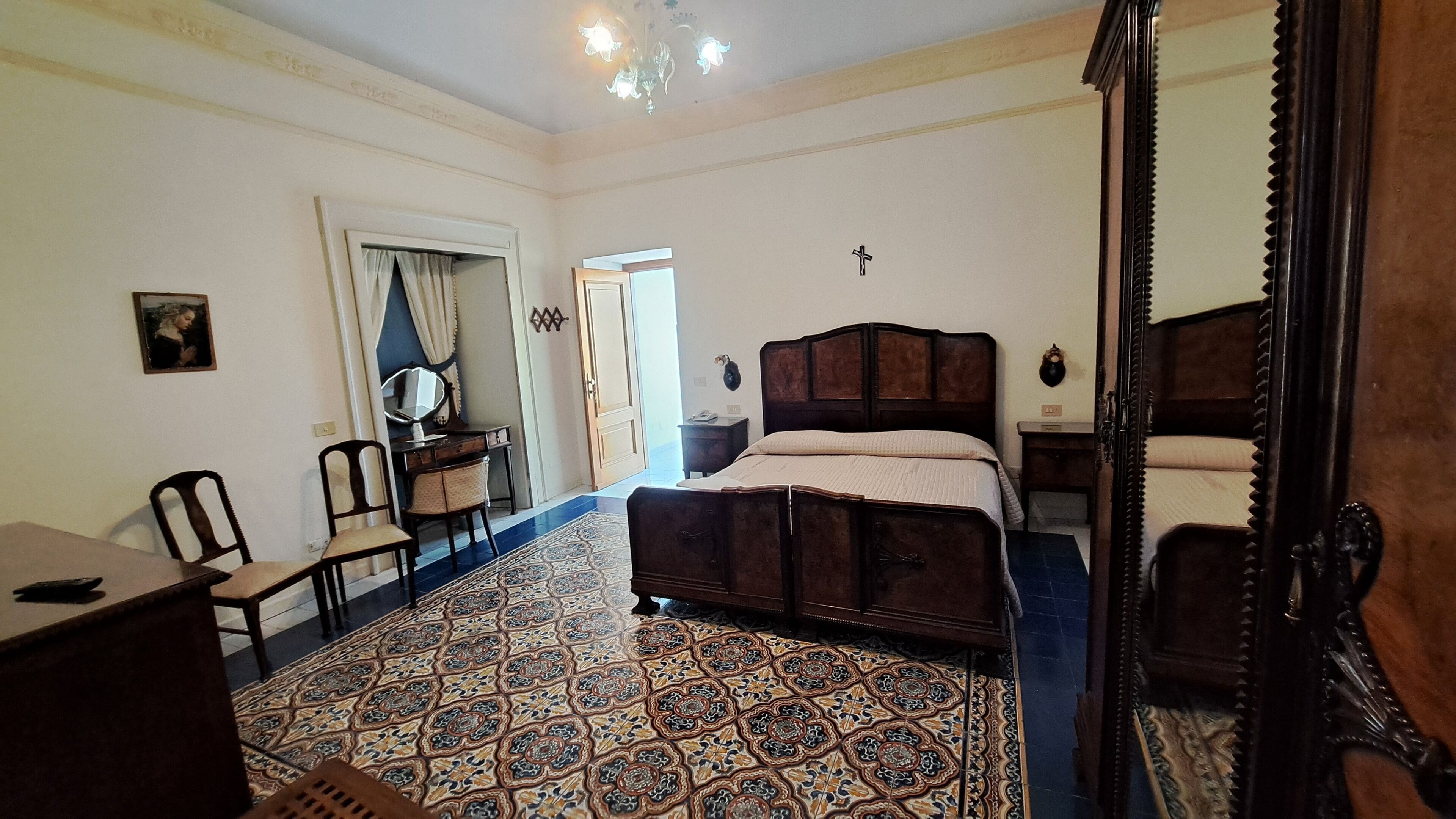 A bedroom with a large bed, a desk, a chair, and a mirror.