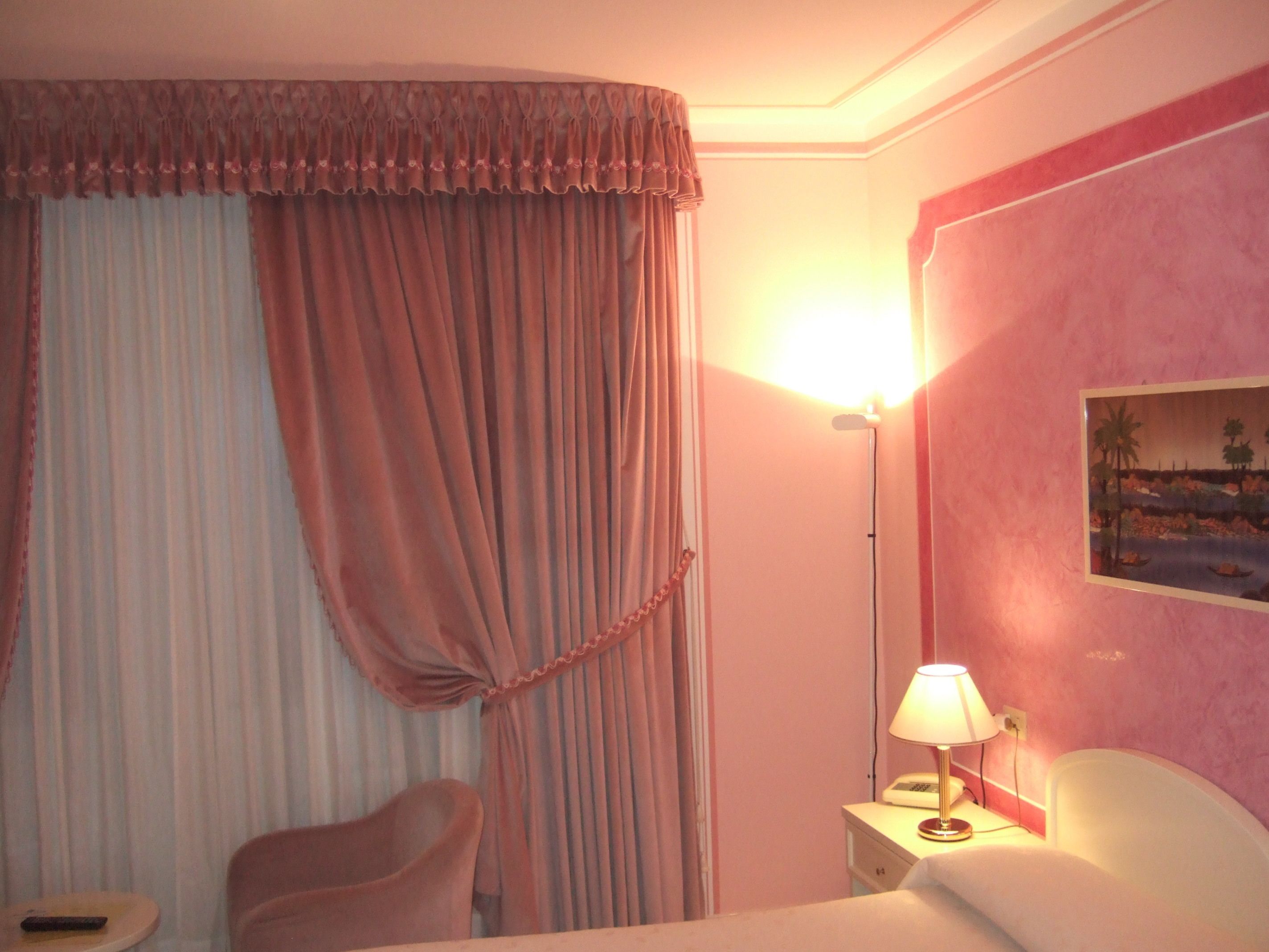 Une chambre d’hôtel avec un lit, une chaise, une table de chevet avec une lampe et un tableau au mur.