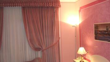 Une chambre d’hôtel avec un lit, une chaise, une table de chevet avec une lampe et un tableau au mur.