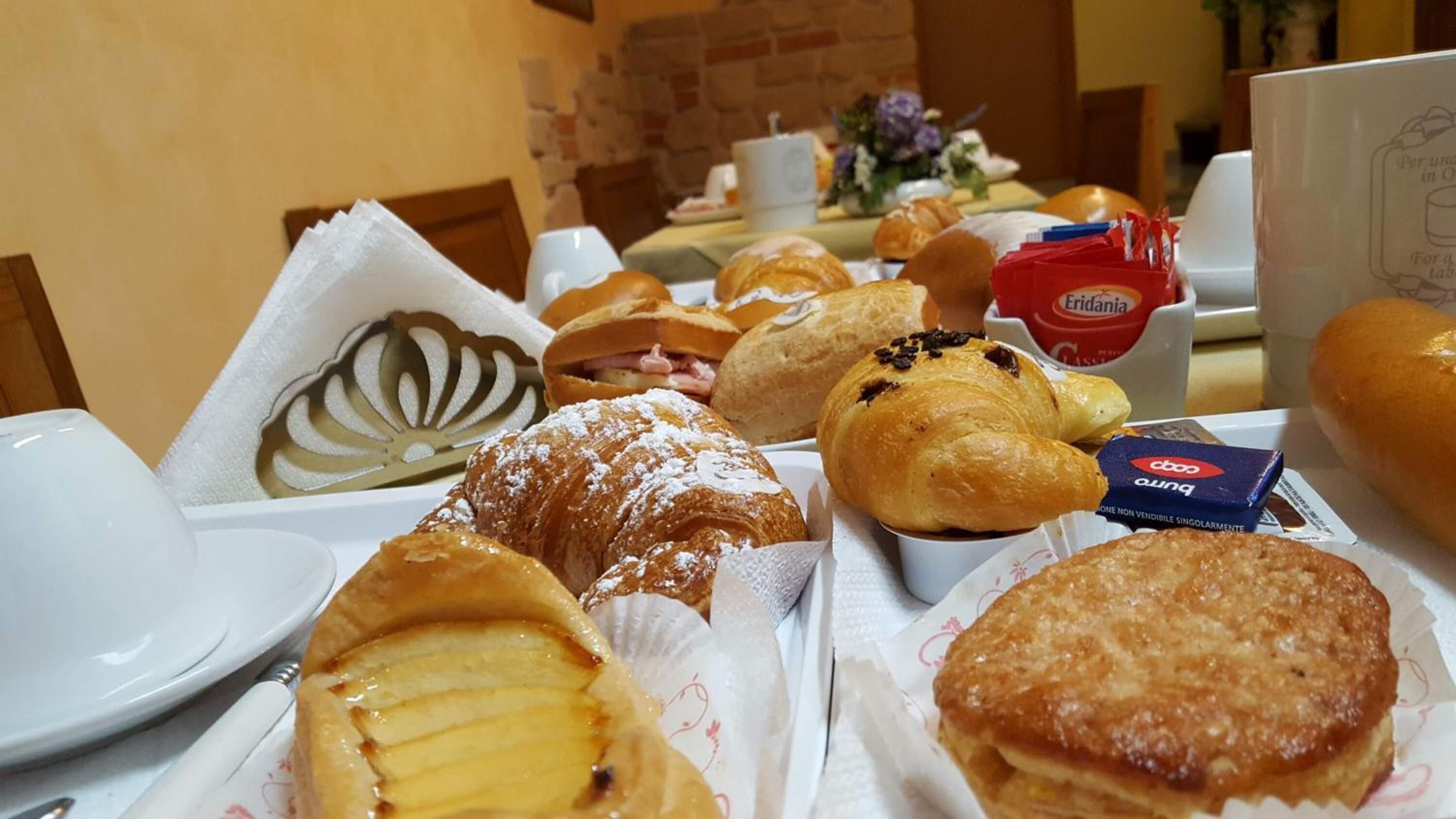 A breakfast buffet with various pastries, including croissants and a tart.