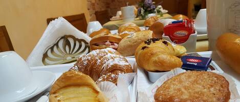 A breakfast buffet with various pastries, including croissants and a tart.