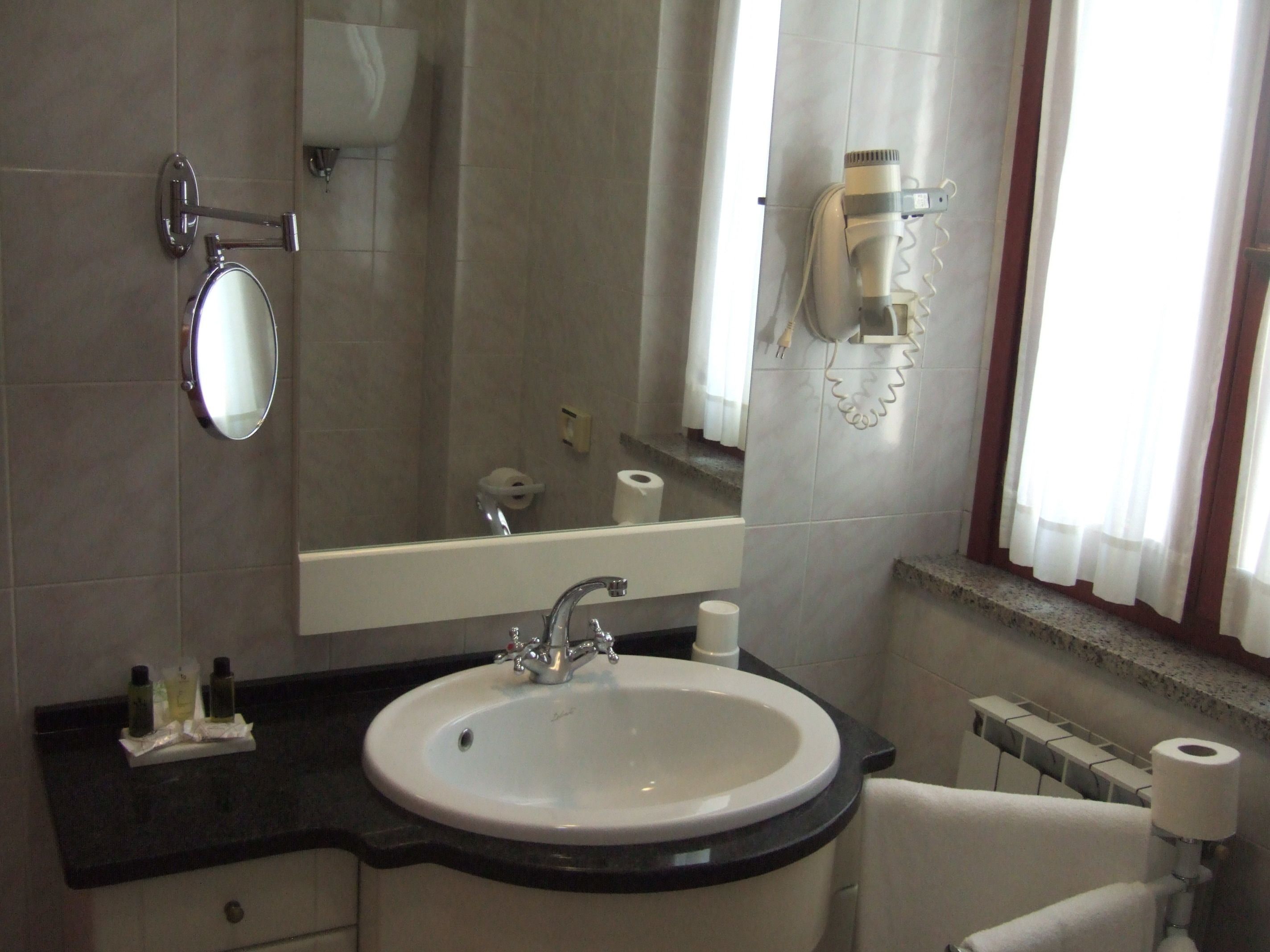 Une salle de bain équipée d’un lavabo, d’un miroir, d’un rouleau de papier toilette et d’un porte-serviettes.