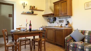 Una cucina con mobili in legno, un tavolo da pranzo con sedie e un divano con una coperta a quadri.
