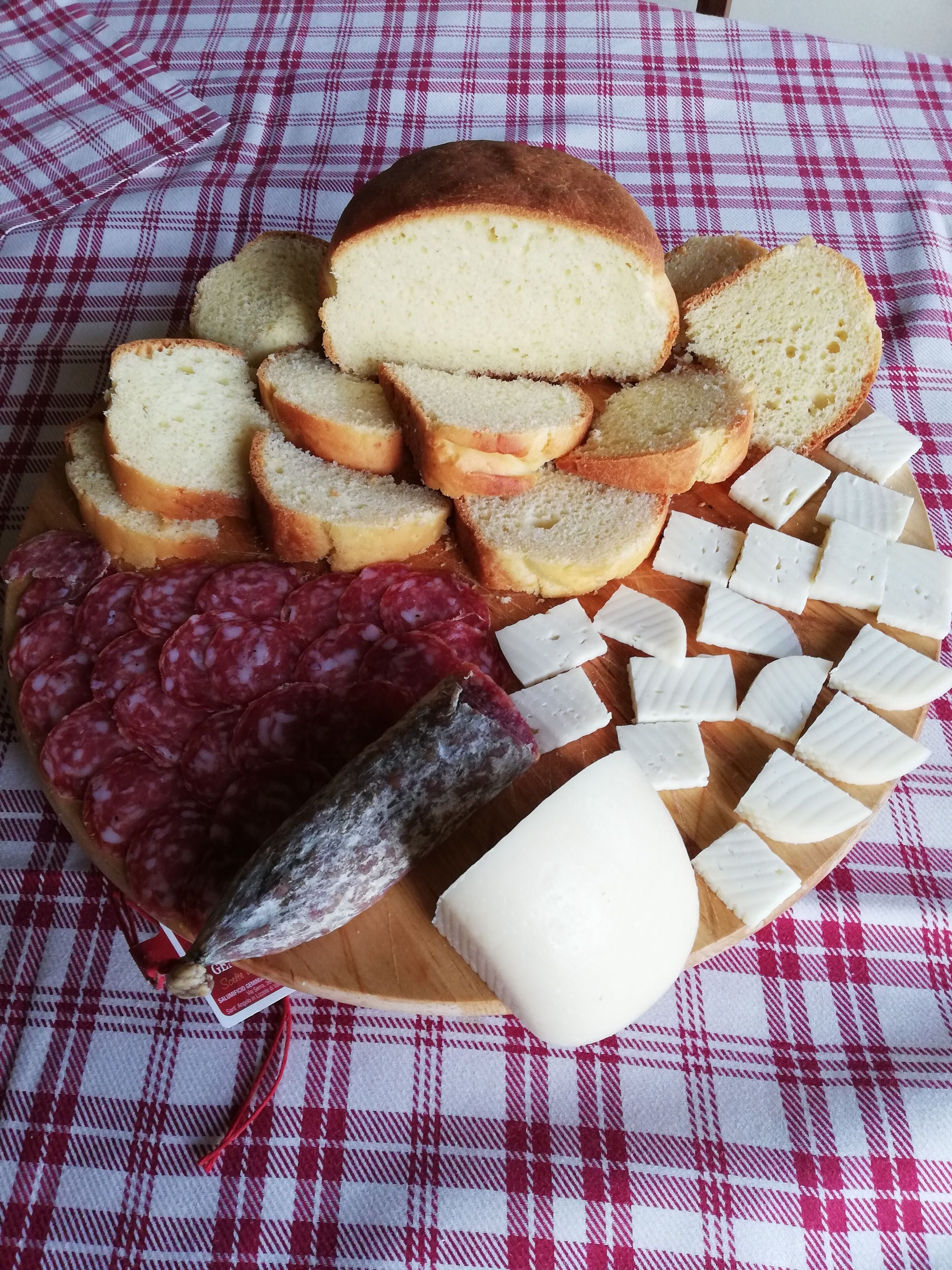 Una tabla de fiambres con pan rebanado, salami y queso sobre una tabla de madera.
